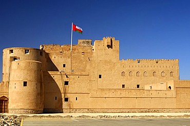 Fort Jabrin flagged with National Flag of Oman, historical clay-made fort in the Dhakiliya Region, Sultanate of Oman, Middle East