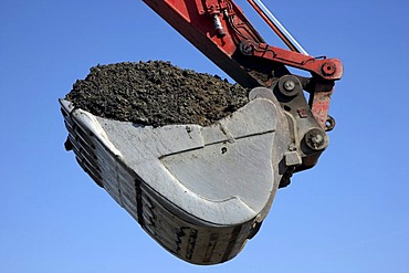 Excavator shovel, laden with soil, construction site