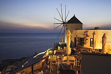 Guests enjoying the sunset on a terrace of a restaurant, Oia, Santorini, Cyclades, Greece, Europe