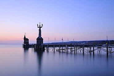 The harbor pier at the entrance of Constance harbor just before sunrise, the tide gauge with the Imperia Statue on it, the town's landmark, and the Molenhaeuschen building at the back, district of Konstanz, Baden-Wuerttemberg, Germany, Europe