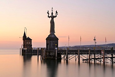 The harbor pier at the entrance of Constance harbor just before sunrise, the tide gauge with the Imperia Statue on it, the town's landmark, and the Molenhaeuschen building at the back, district of Konstanz, Baden-Wuerttemberg, Germany, Europe