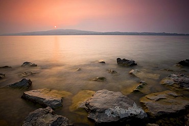 Red sunset through a lot of dust on Lake Constance in Berlingen, Switzerland, Europe