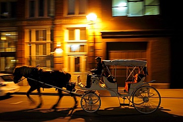 Horse-drawn carriage for tourists driving at night through the streets of the historic old town of Montreal, Quebec, Canada