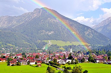 View over Oberstdorf with a rainbow in front of Schattenberg Mountain with the Schattenberg ski-jump, Oberallgaeu, Bavaria, Germany, Europe