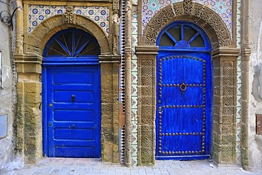 Blue doors of a house, doors surrounded by stone carvings and tile mosaics, Essaouira, Morocco, Africa