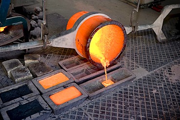 Bronze being poured into moulds, workers in an art foundry