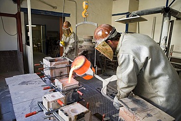 Working in an art foundry, liquid bronze being poured into moulds