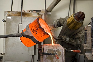 Working in an art foundry, liquid bronze being poured into moulds