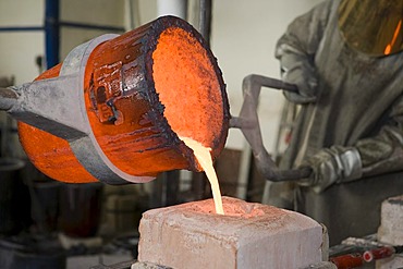 Working in an art foundry, liquid bronze being poured into moulds