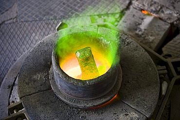 Bronze being heated in a melting pot on a gas stove in an art foundry