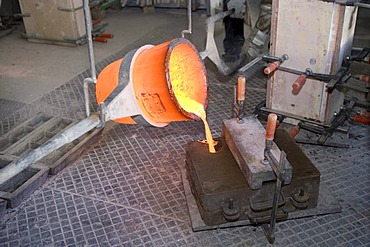 Working in an art foundry, liquid bronze being poured into moulds