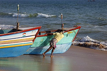 Fishermen pushing their fishing boat into the sea, Somatheeram Beach, Malabarian Coast, Malabar, Kerala state, India, Asia