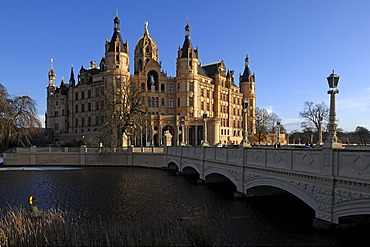 Schwerin Castle and Schlossbruecke bridge against a blue sky behind the frozen Schwerin Lake, the castle was built between 1845 and 1857 during romantic historicism, Lennestrasse 1, Schwerin, Mecklenburg-Western Pomerania, Germany, Europe