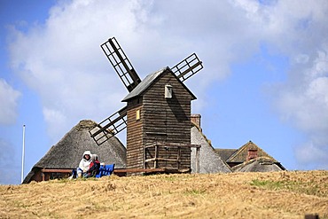 Woman and child sitting under old wooden corn mill from 1926 on the Halligen island of Langeness, Schleswig-Holstein, Germany, Europe