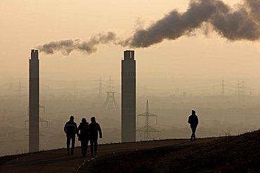 People walking across Hoheward waste dump, in front of chimneys of the AGR incinerating plant, Herten, North Rhine-Westphalia, Germany, Europe