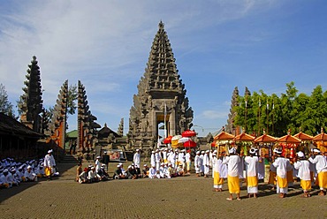 Balinese Hinduism, gathering of believers, ceremony, believers in bright temple dress carrying colourful parasols and shrines, temple tower and in the back the split gate, Candi bentar, Pura Ulun Danu Batur temple, Batur village, Bali, Indonesia, Southeas