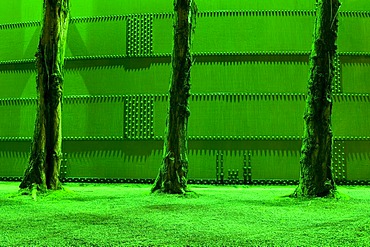 Green-lit tree trunks and steel wall in the former steelworks, Landschaftspark Duisburg Nord landscape park, Ruhrgebiet area, North Rhine-Westphalia, Germany, Europe