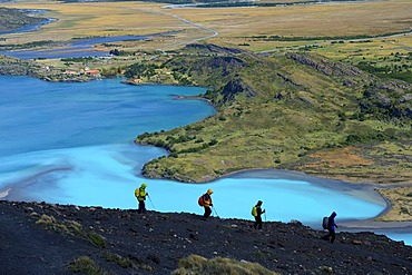 Hikers on a dark rock in front of the Rio Paine River, Patagonia, Chile, South America