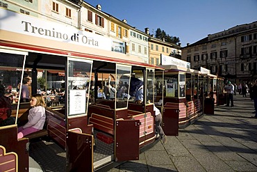 Orta San Giulio, Lago d'Orta, main square with little train for sight-seeing tours and waterfront antique palaces, Novara, Piedmont, Italy, Europe