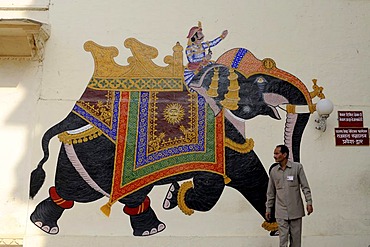 Indian in front of the mural of an elephant with a rider in the city palace, Udaipur, Rajasthan, North India, India, South Asia, Asia