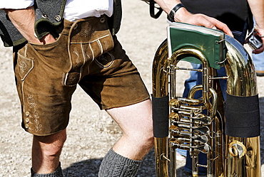 Man in traditional lederhosen leather pants leaning on a tuba, brass band, St. Wolfgang, Salzkammergut region, Upper Austria, Austria, Europe