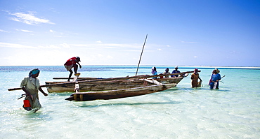 A fishing boat brings brightly dressed women to the beach, Zanzibar, Tanzania, Africa