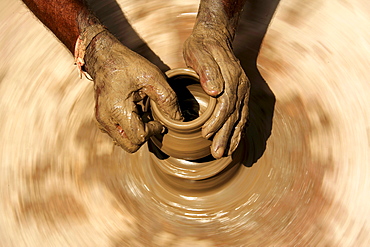 Hands of a potter, 58, in Dunjarpur, forming a piece of pottery on the potter's wheel, Rajasthan, India, Asia