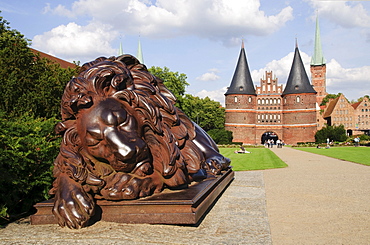 Sculpture Sleeping Lion in front of the Holstentor, Holsten Gate, in Luebeck, Schlewig-Holstein, Germany, Europe