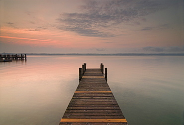 Sun rising over a pier in the calm Lake Starnberg, Bavaria, Germany, Europe