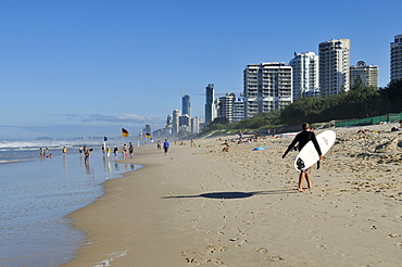 Man with surfboard on the beach of Surfers Paradise, Gold Coast, Queensland, Australia