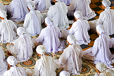 Seated Nuns praying, ceremonial midday prayer in the Cao Dai temple, Tay Ninh, Vietnam, Asia