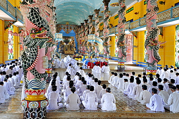 Praying devout men and women, ceremonial midday prayer in the Cao Dai temple, Tay Ninh, Vietnam, Asia