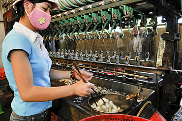 Woman with face mask working in a silk factory, cocoons floating in water, silk is removed and wound on spindles, Dalat, Central Highlands, Vietnam, Asia