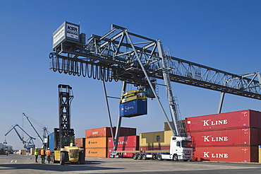 Container Terminal Bonn, gantry crane loading containers onto a truck, workers standing beside a container forklift at the front, port cranes at the rear, North Rhine-Westphalia, Germany, Europe