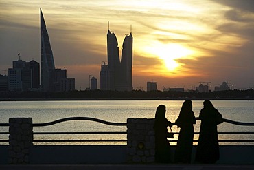 Skyline of the Corniche as seen from King Faisal Highway, Muharraq side, World Trade Center buildings, left, beside the towers of the Financial Harbour Complex, pedestrians walking along the Corniche in the evening, capital city, Manama, Kingdom of Bahrai