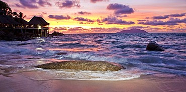 Typical granite rock of the Seychelles on the beach at dusk near Glacis, Sunset Beach Resort at back, island of Mahe, Seychelles, Indian Ocean, Africa