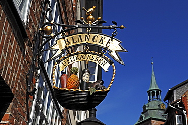 Advertising sign of a delicatessen shop, tower of Michaeliskirche Church in the back, Lueneburg, Lower Saxony, Germany, Europe