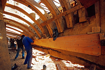 Shipwright under the hull of a trawler in the shipyard of Essaouira, Morocco, North Africa