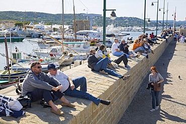 Tourists sitting in the harbour and watching the boats of the "Les Voiles de Saint-Tropez" sailing regatta in Saint-Tropez, Departement Var, Cote d'Azur, Provence, Southern France, France