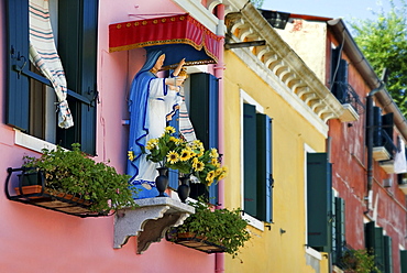 Madonna figure at the colorfully painted houses of Burano, Venice, Italy, Europe