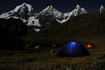 Tents glowing in the dark at Laguna Carhuacocha, from left, Yerupacha, Yerupacha Chico, and Jirishanca behind, Cordillera Huayhuash, Peru, South America