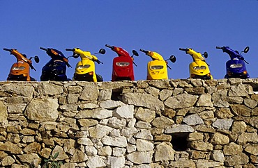 Mopeds lined up by a stone wall, Mykonos city, Mykonos, Greece, Europe