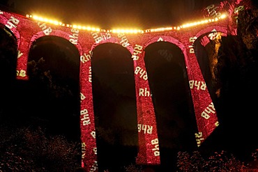 Irrigation water viaduct lit up with the letters 'RhB' to celebrate the acceptance of the "Rhaetische Bahn Railway in Albula/Bernina" as a UNESCO World Heritage Site, Filisur, Graubuenden, Switzerland, Europe