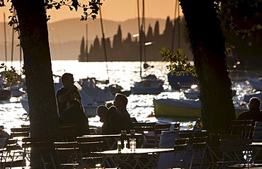 Tourists sitting in a restaurant at sunset on the shores of Lake Garda, Lago di Garda, Lombardy, Italy, Europe