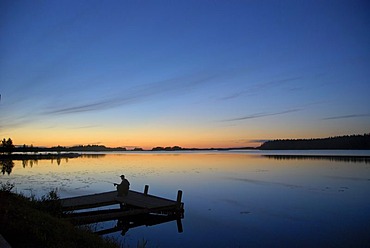 Fisher on a jetty in evening light, Saimaa Lake District, Finland, Europe