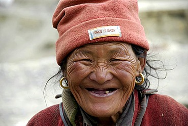 Portrait old woman wearing a fleece cap with sign Take It Easy Phu Nar-Phu Annapurna Region Nepal