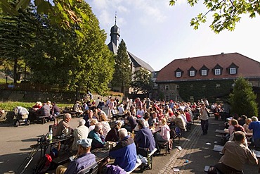 Kreuzberg in the Rhon Rhoen mountains district of Rhon-Grabfeld Rhoen-Grabfeld Lower Frankonia Bavaria Germany pilgrims and tripper in the open air restaurant near the pilgrimage church