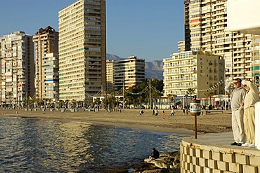 Tourists looking out on the beach of Benidorm, Playa de Levante, Costa Blanca, Spain