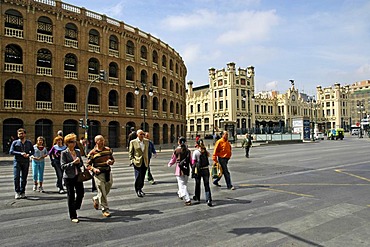 People crossing the street on a zebra crossing in front of a bullfight arena and the main station, Valencia, Spain