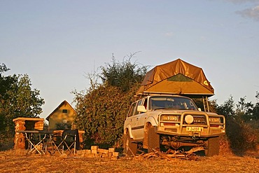 Toyota Land Cruiser 4x4 with tent loaded onto its roof at a campsite in Ihaha, Chobe National Park, Botswana, Africa